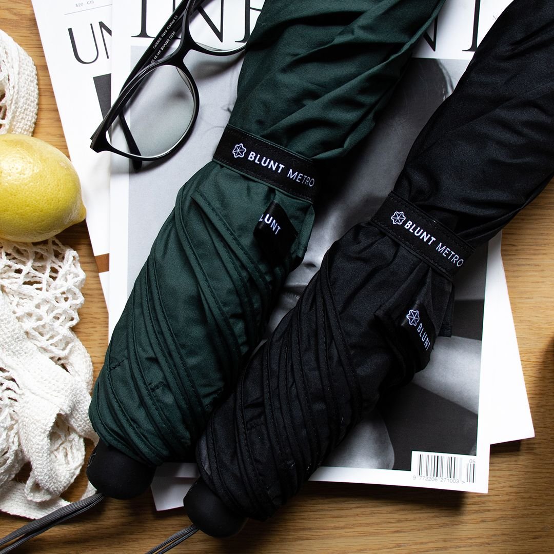 A black and a green folded umbrellas in sleeves on a table