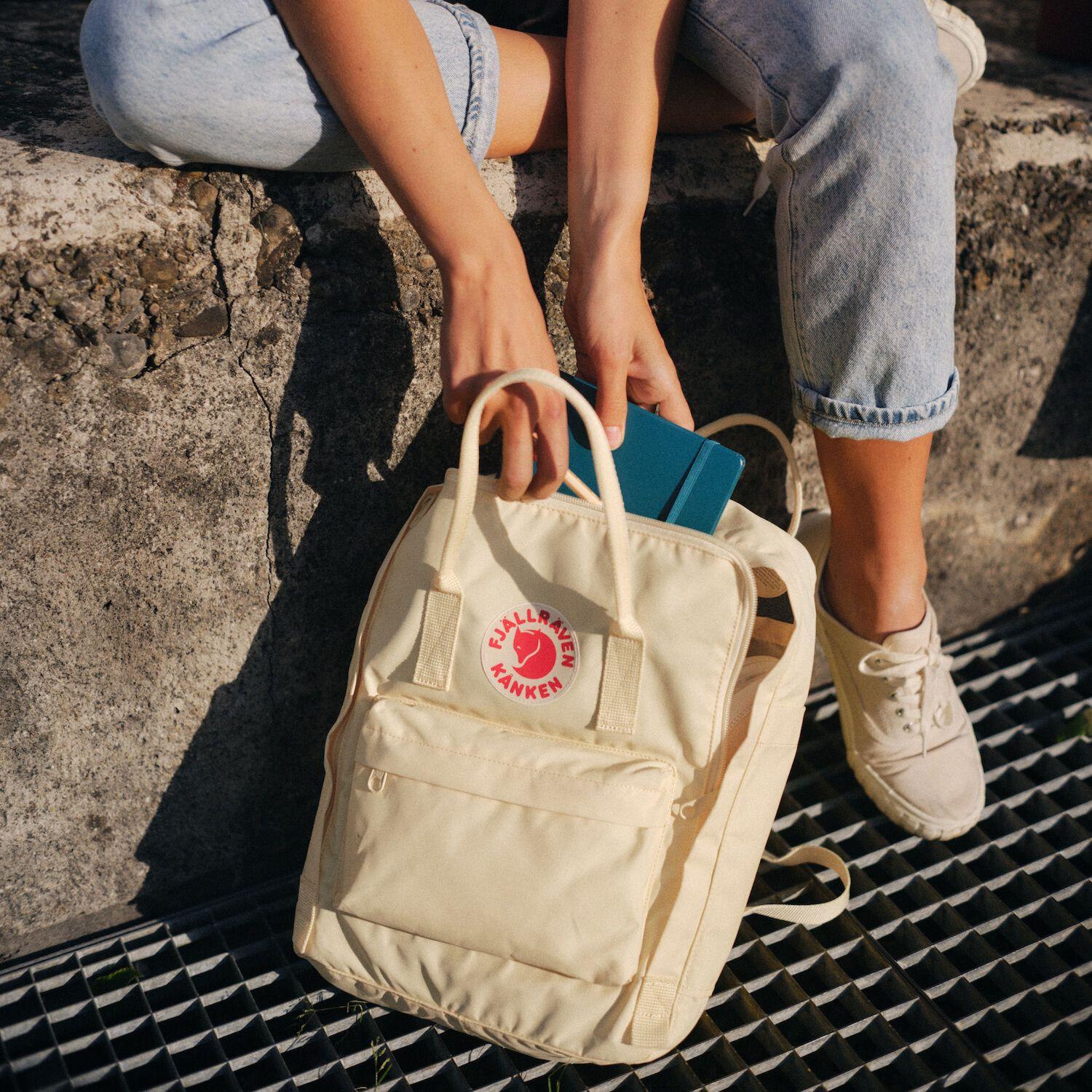 Female pulling a diary out of a Kanken backpack