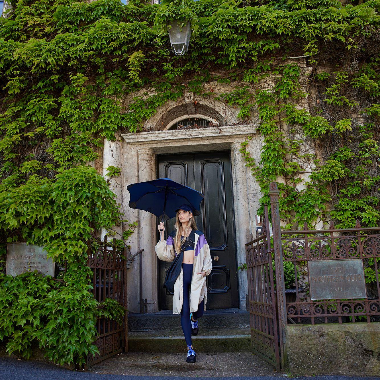 woman in activewear with dark blue umbrella