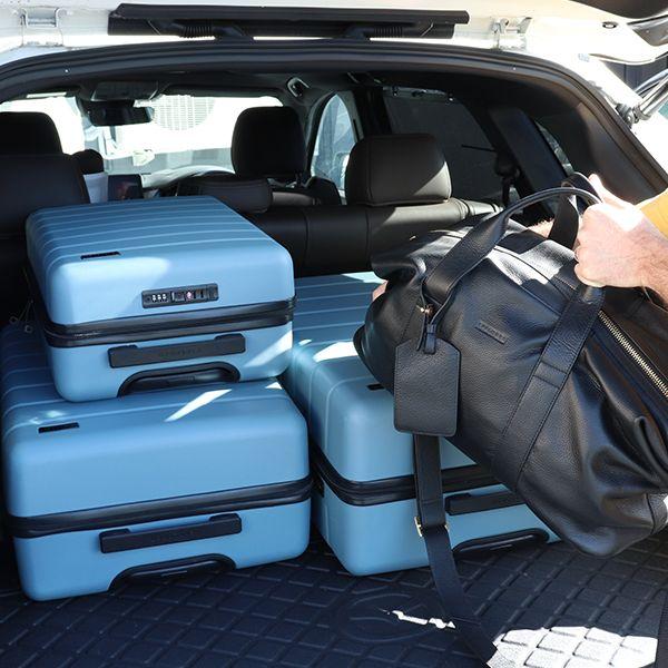 Man packing a boot with three arlo cases in ocean and a black explorer duffle