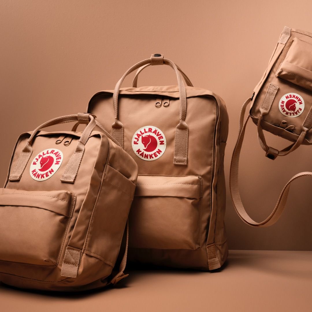 Fjallraven Kanken Backpack in Ochre on the beach, with sunglasses and scarf tied to it