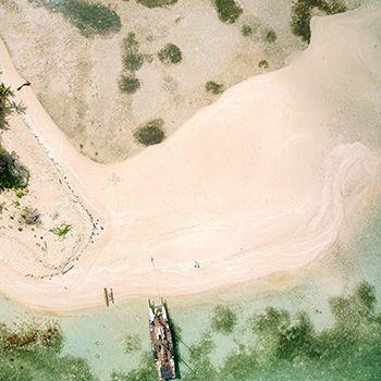 Birds eye view of an island, with a boat in the ocean