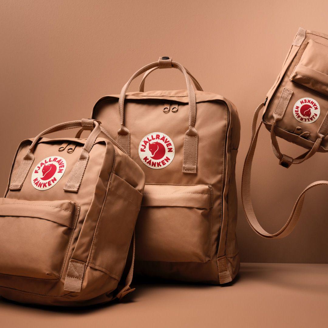 Fjallraven Kanken Backpack in Ochre on the beach, with sunglasses and scarf tied to it
