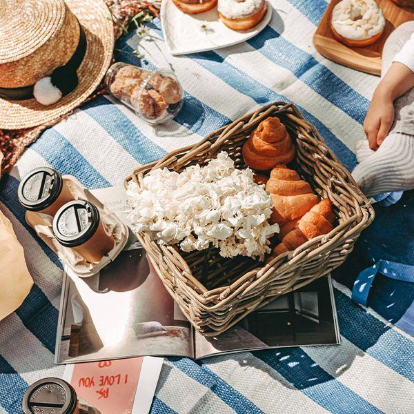 picnic with coffee, bagels, croissants on a striped picnic blanket