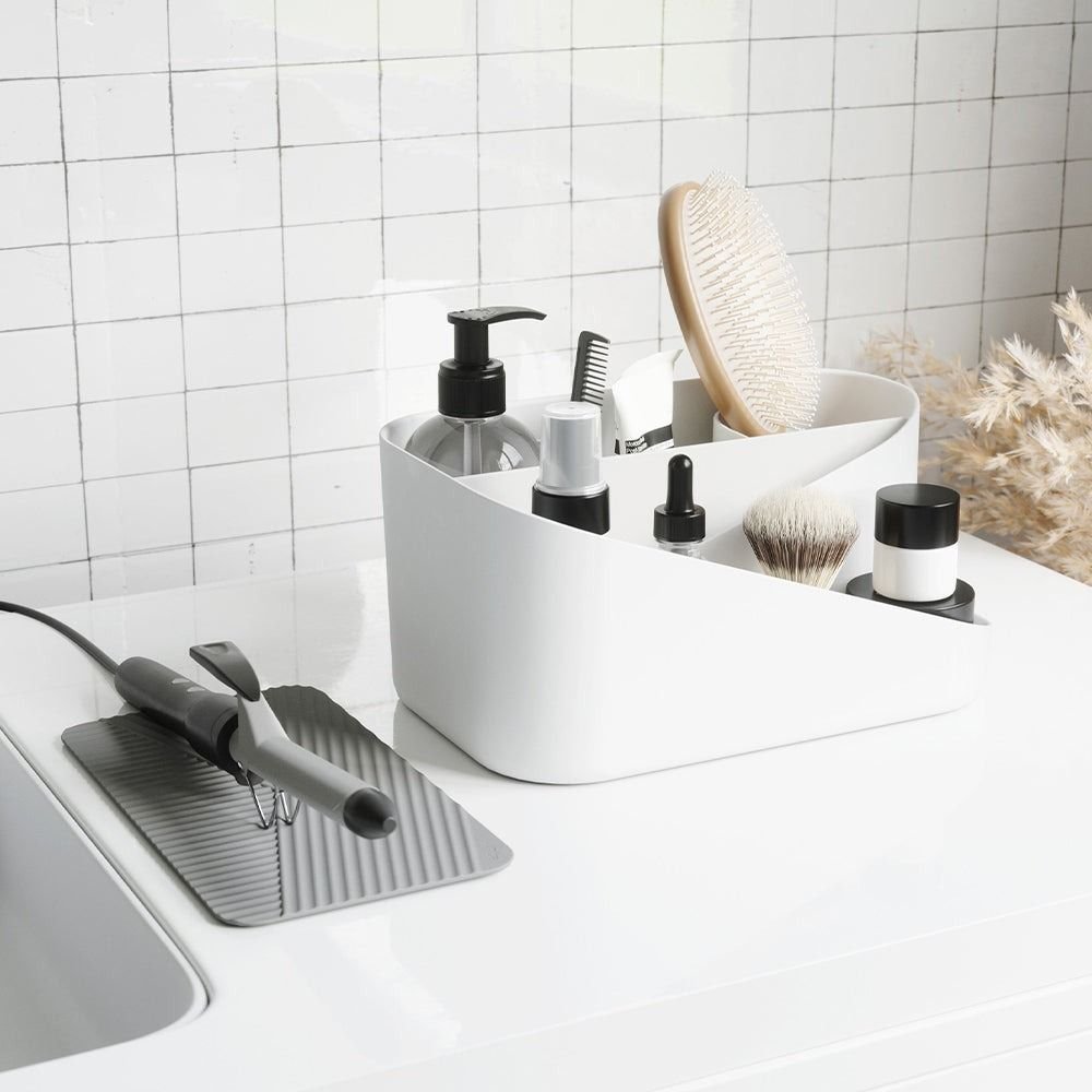 Umbra Glam Hair Tool Organiser with hair tools and toiletry items weithin on a bathroom bench. 