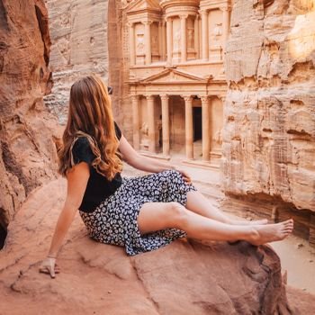 Girl looking at rock sculptures, sitting on a rock